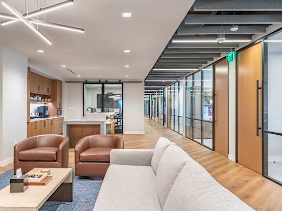 A modern office lounge with brown leather chairs and a white sofa.