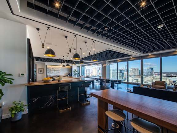A modern kitchen with a long wooden counter and bar stools.