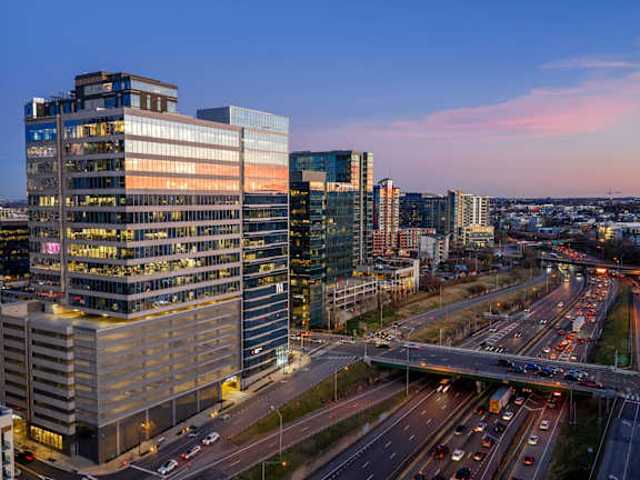 A cityscape with a highway and buildings during twilight.