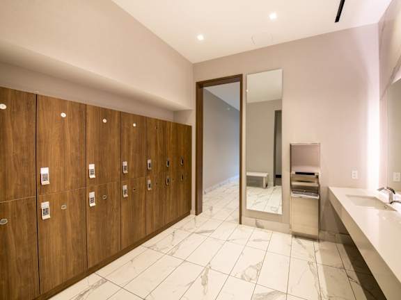 A bathroom with a row of wooden lockers and a marble floor.