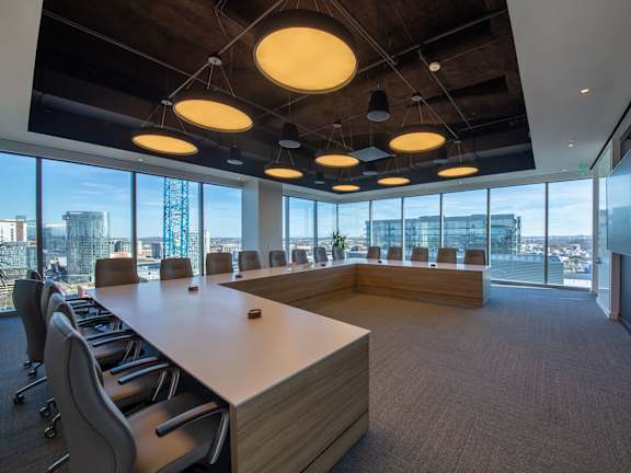 A conference room with a long table and chairs, and a view of the city outside the windows.