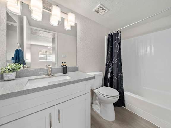 A white bathroom with a toilet, sink, and shower.