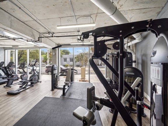 a gym with weights and other exercise equipment in a building with windows