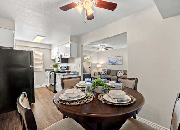 A dining room with a table set for two and a ceiling fan.