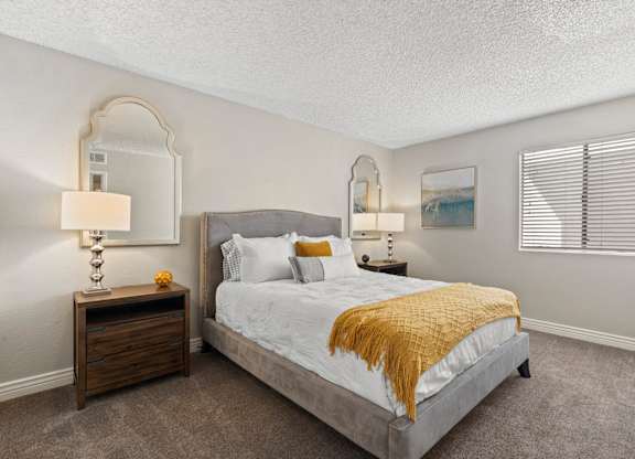 A bedroom with a bed, nightstand, and two wall lamps.