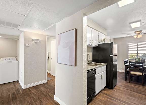 A kitchen with black appliances and wooden floors.