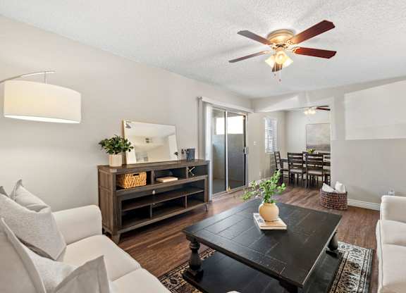 A living room with a white couch, a wooden coffee table, and a ceiling fan.