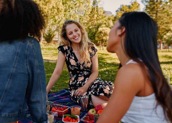 Three women having a picnic in a park.