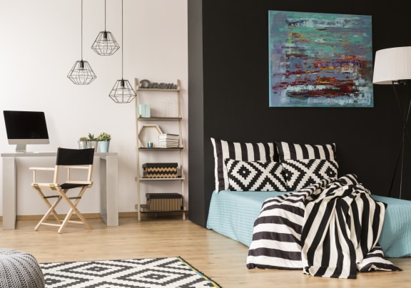 a bedroom with a bed with black and white bedding and a desk with a computer