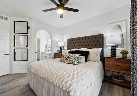 A bedroom with a large bed and a ceiling fan.