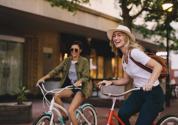 two women riding bikes down the street