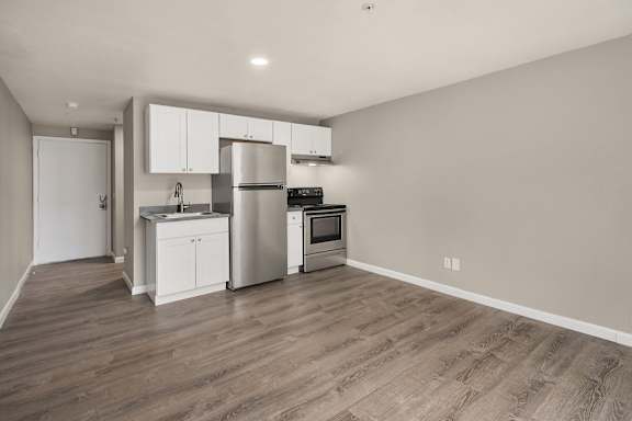 A kitchen with a refrigerator, oven, and sink.