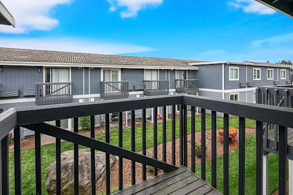 A balcony overlooks a grassy area and a baseball diamond.