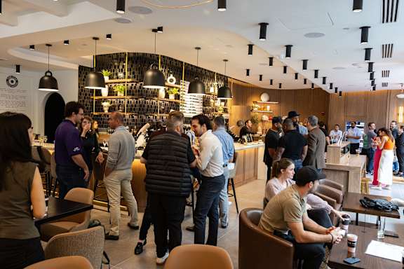 A group of people are gathered in a room with a bar area.