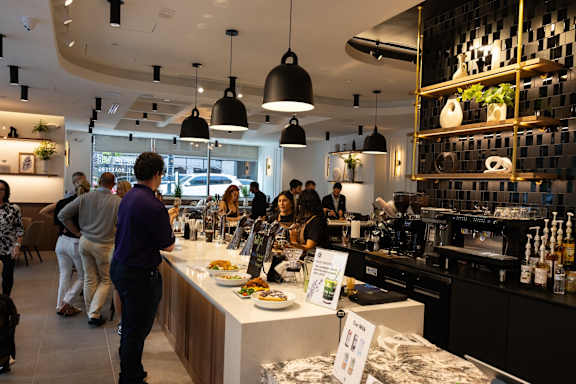 A group of people are standing in a restaurant with a counter in the foreground.
