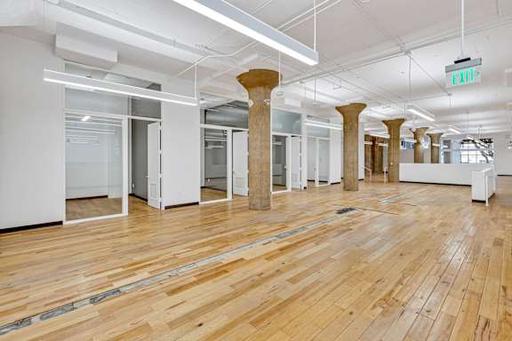 A room with wooden floors and white walls with columns in the middle.