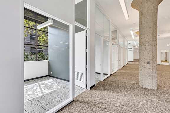 A long hallway with a stone pillar and glass doors.