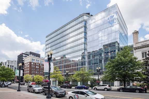 A modern glass building is the centerpiece of a city street scene.