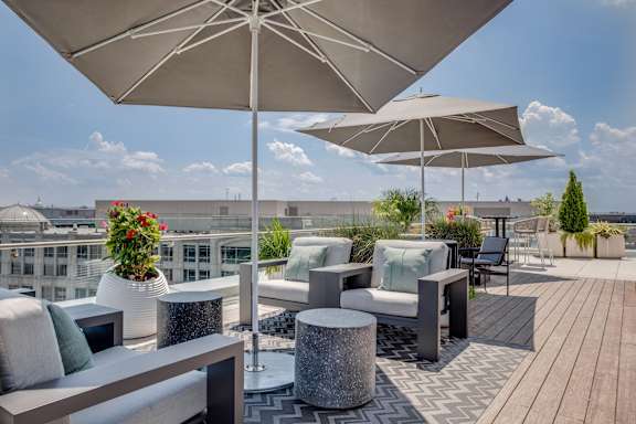 A patio with a large umbrella and a table with a vase of flowers on it.