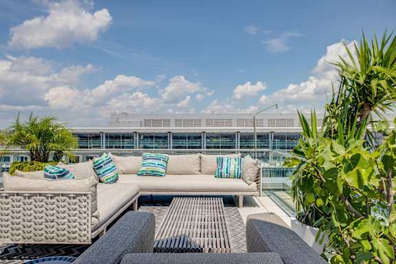 A patio with a couch and pillows overlooking a building.