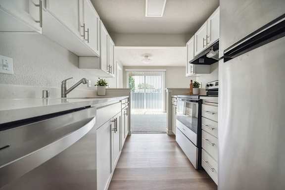 A modern kitchen with white cabinets and stainless steel appliances.