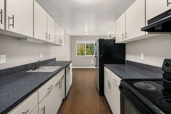 A kitchen with black appliances and white cabinets.