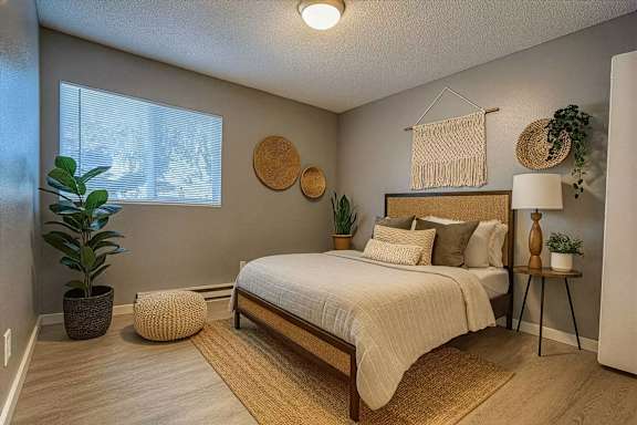 A bedroom with a bed, a potted plant, and a wall hanging.