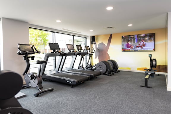 a gym with cardio equipment and a tv on the wall at The Trilogy Apartments, Manchester, M15 4RU
