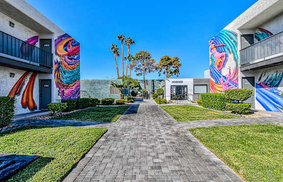 A walkway leads between two buildings with colorful murals on the walls.