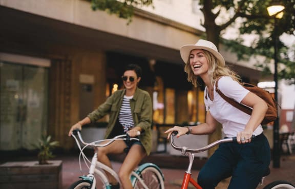 two women riding bikes down the street