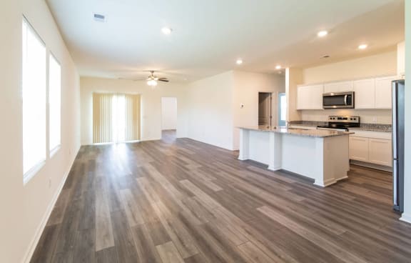 an empty living room and kitchen with wood flooring