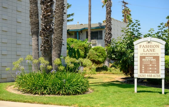 a swimming pool with lounge chairs and umbrella in front of a building with palm trees in the