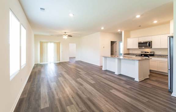 an empty living room and kitchen with wood flooring