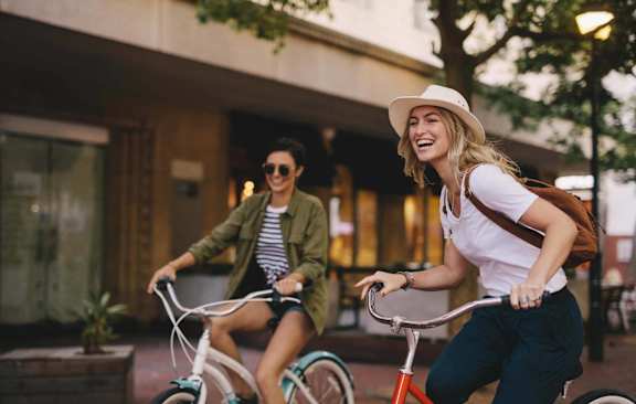 Two people riding bicycles in an urban setting.