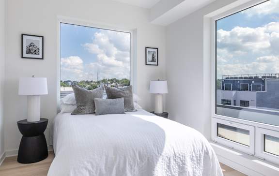A bedroom with a large bed, two lamps, and pictures on the wall.