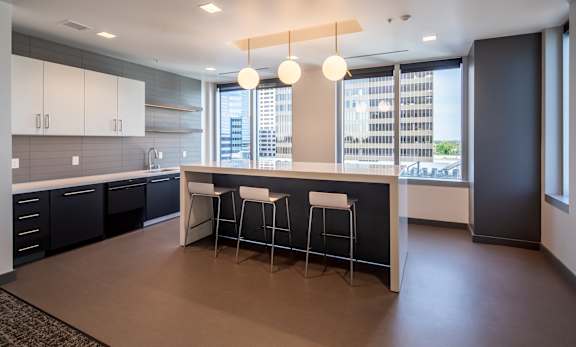 A modern kitchen with a bar stool and a view of the city.