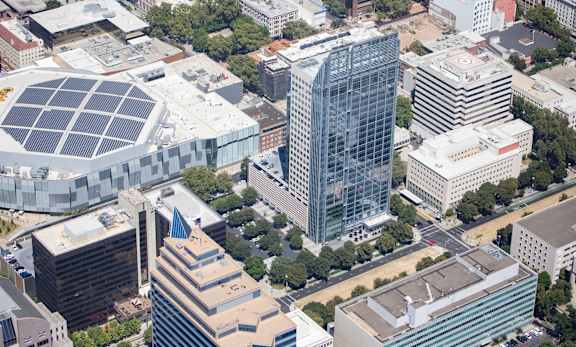A cityscape with a large building featuring a solar panel on its roof.
