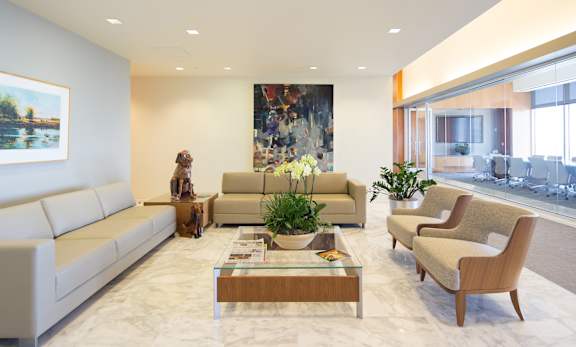 A living room with a white sofa, a wooden coffee table, and a large painting on the wall.