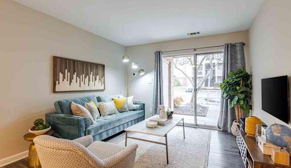 A living room with a blue couch and a television on a wooden cabinet.