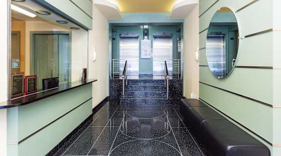 A hallway with a black floor and a bench on the right side.