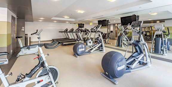 A gym with a variety of exercise equipment including treadmills, stationary bikes, and weight machines.