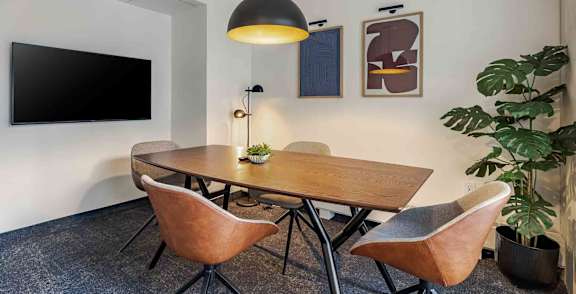 A room with a plant, chairs, and a table.
