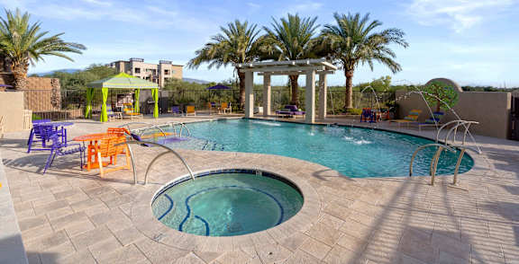 A pool surrounded by palm trees and a building.