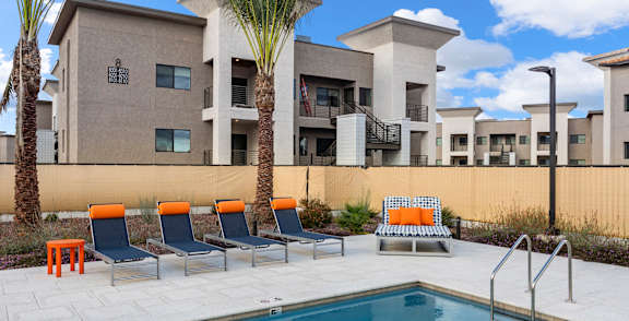 A pool surrounded by palm trees and a building.