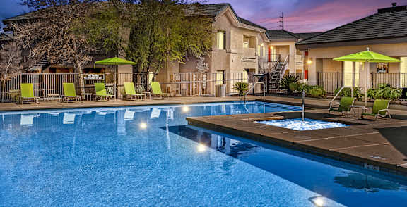 A pool surrounded by palm trees and a building.
