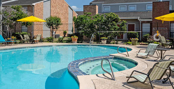 A pool surrounded by palm trees and a building.