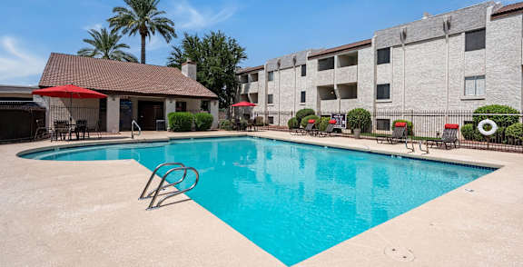 A pool surrounded by palm trees and a building.