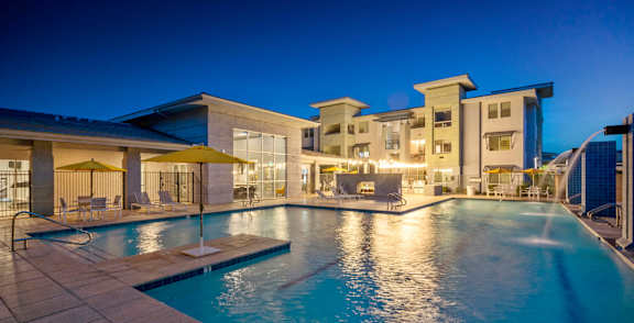 A pool surrounded by palm trees and a building.