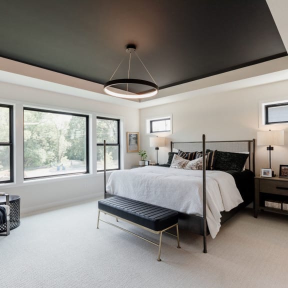 the master bedroom has a black ceiling and white walls and a bed and a chair
