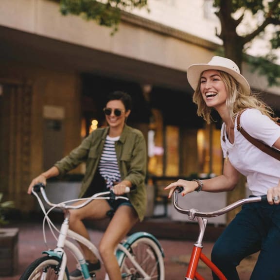 two women riding bikes down the street